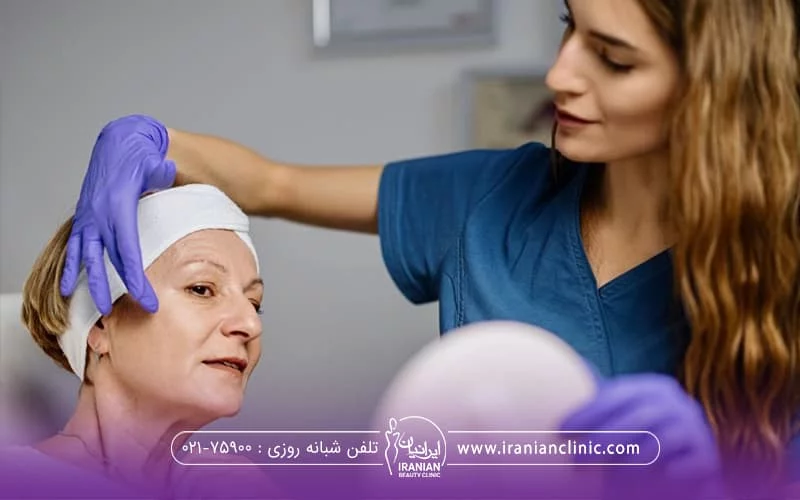 دکتری با موهای بلند که دست کش آبی به دست دارد و دستش را از بالا سر زنی که نشسته آورده است که در حال بررسی پوست وی برای انجام اندو لیفت میباشد